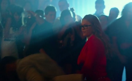 De óculos e vestido vermelho, Rousey aparece em "Os Mercenários 3". Foto: Reprodução/YouTube